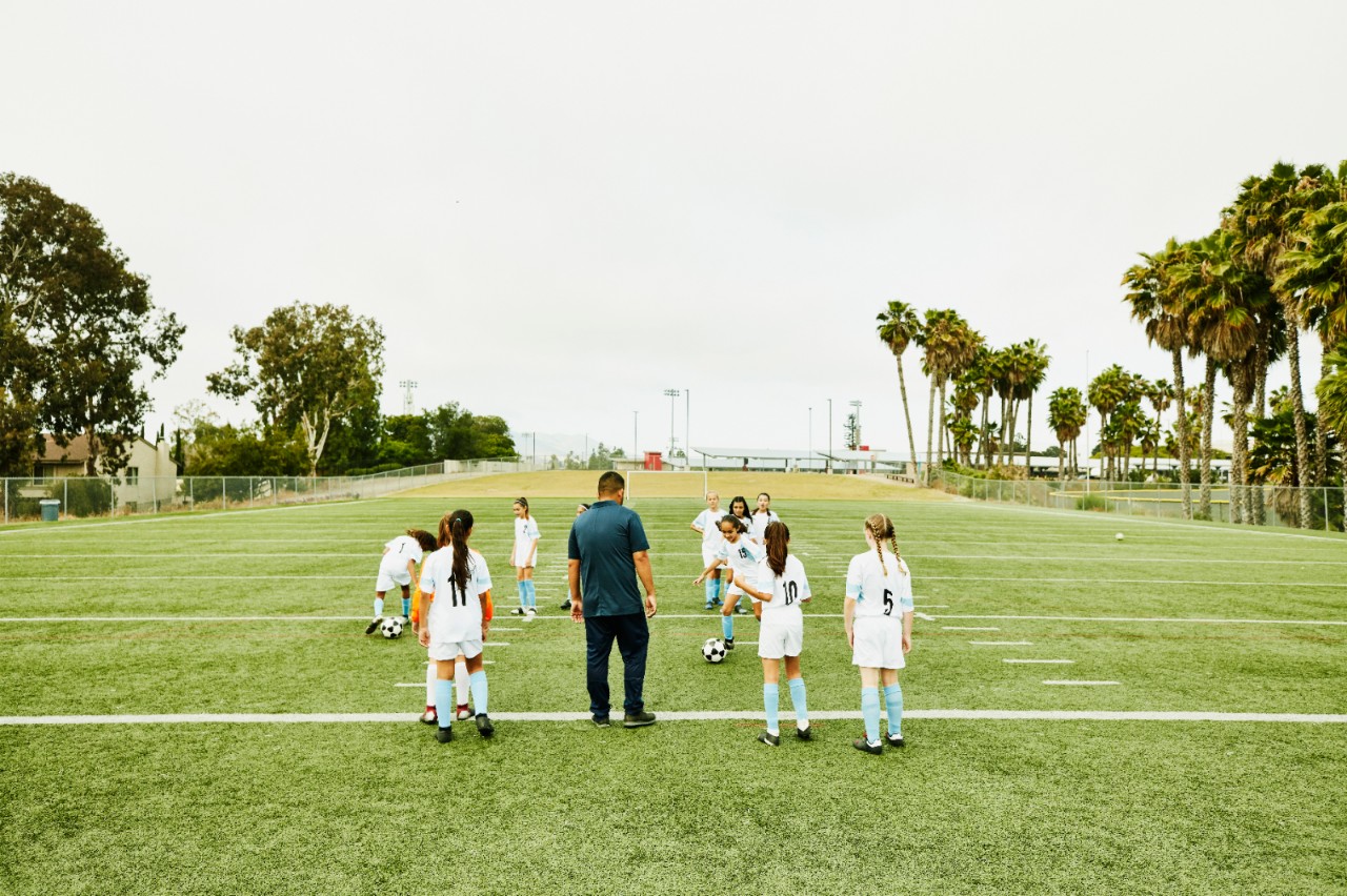 足球教练看着年轻的女球员在训练中进行训练