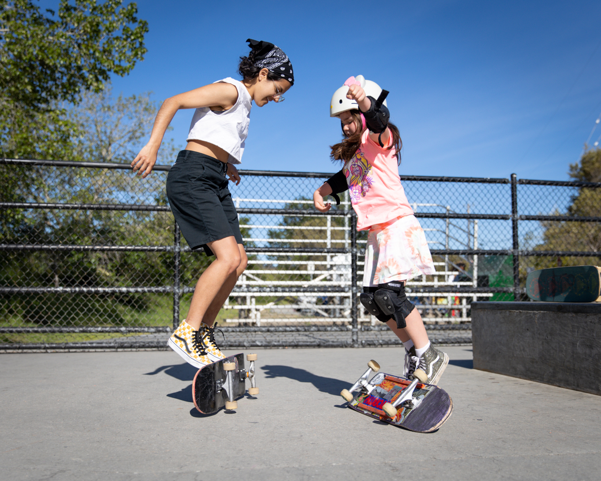 两个女孩用脚翻转滑板。
