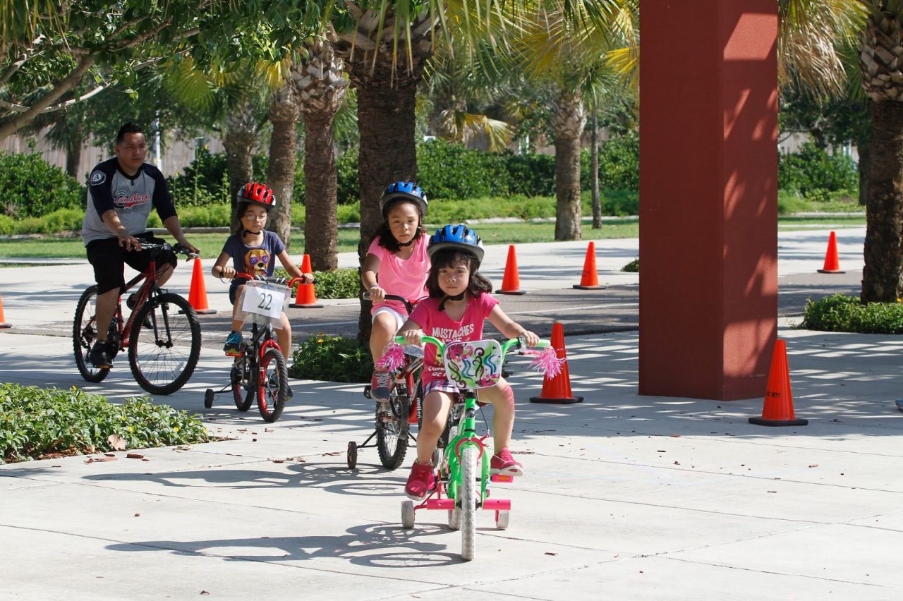父母和孩子们骑着自行车穿过公园。