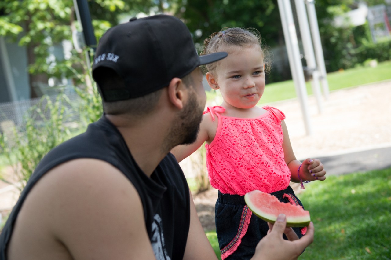 2016年8月18日，周四，在新罕布什尔州曼彻斯特哈里曼公园举行的第九届年度野餐和街区派对上，迈克·克鲁兹给他3岁的女儿米凯拉·克鲁兹喂西瓜。野炊是一个将社区成员聚集在一起的机会，但今年的特别之处在于公园里安装了新的游乐场。