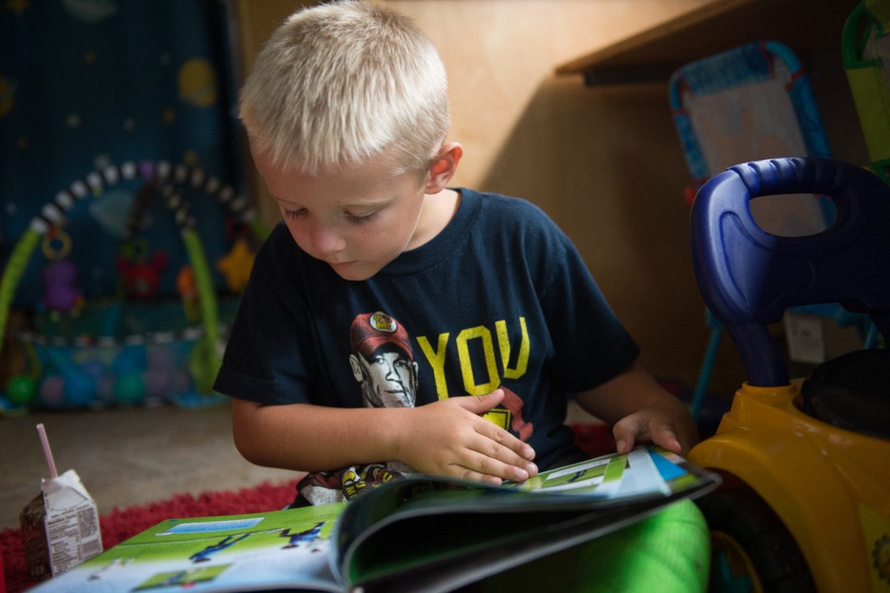 5岁的Brantley Lantz在“课堂之外的学习”巴士上一边读书一边喝牛奶，巴士停在Crellin小学门前。巴士上设有图书馆和儿童学习游戏，并提供健康零食。