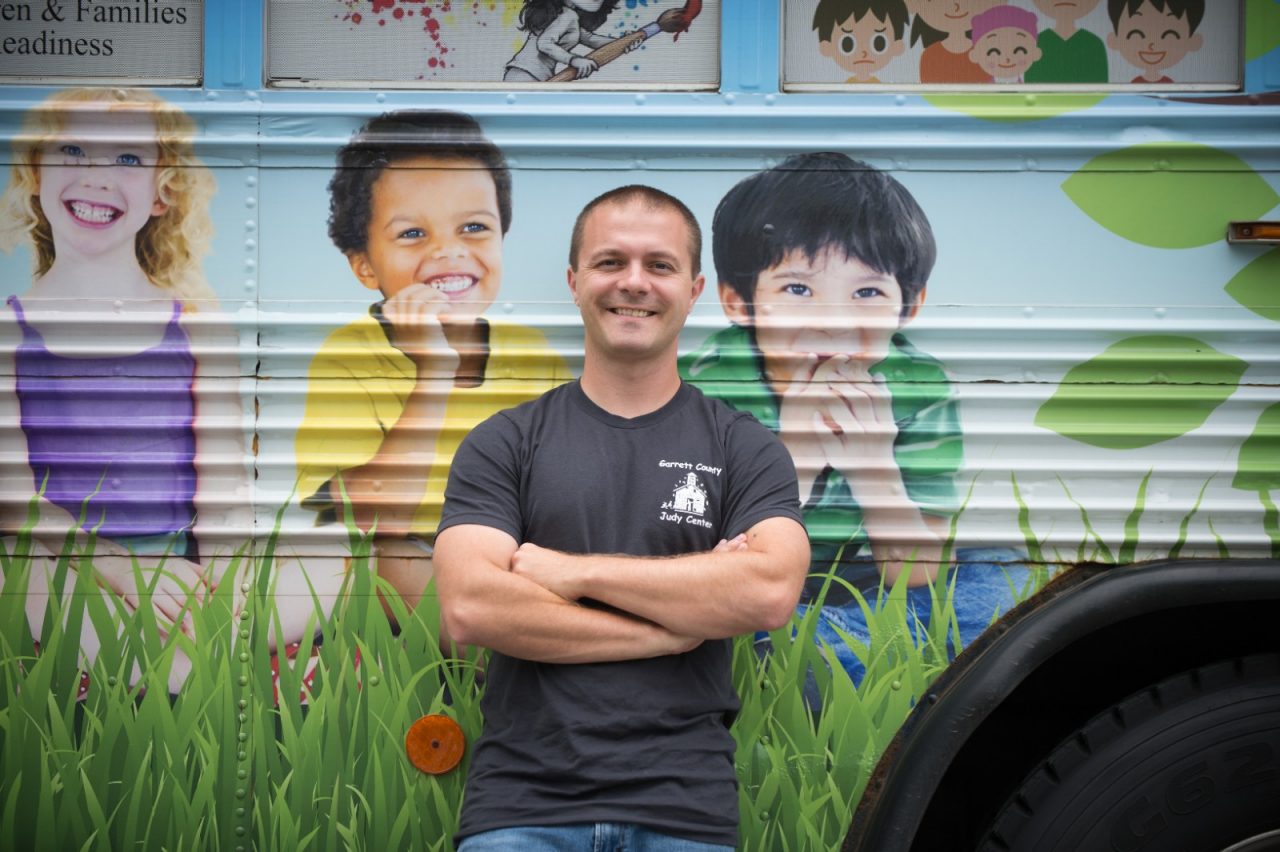 在克雷林小学前，史蒂夫·克内普站在“超越课堂的学习”巴士旁边。巴士上设有图书馆和儿童学习游戏，并提供健康零食。